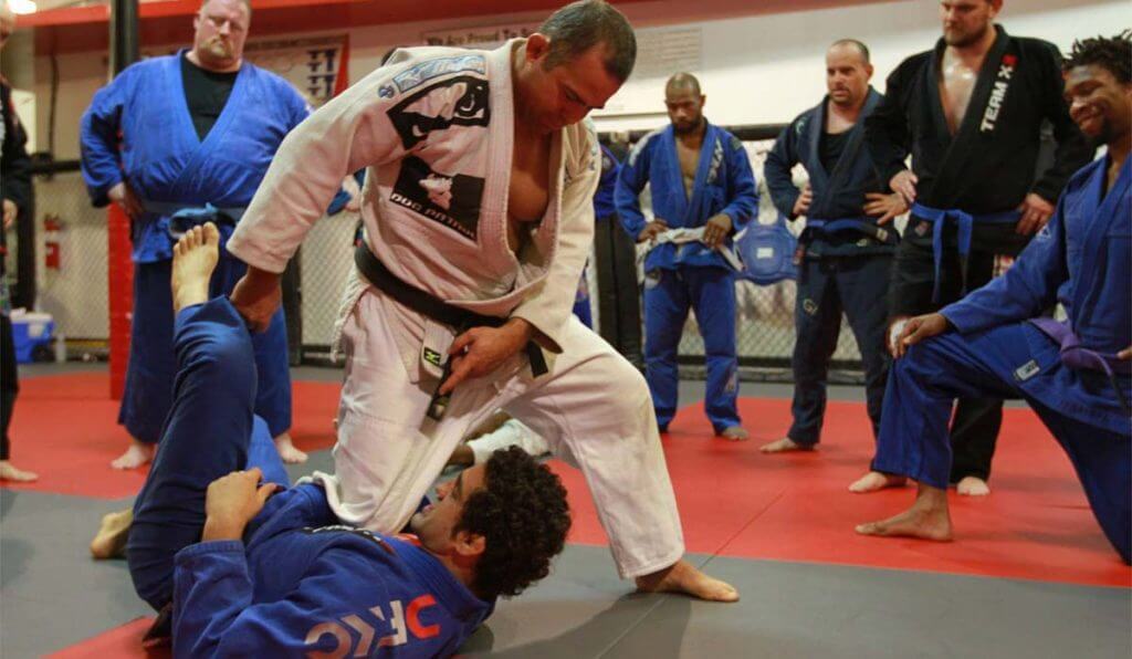 Instructor demonstrating a grappling move in a BJJ class.