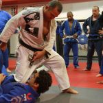 Instructor demonstrating a grappling move in a BJJ class.