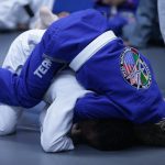Two individuals grappling in Brazilian Jiu-Jitsu training, wearing blue and white gis.
