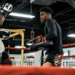Male Muay Thai trainer holding pads during a training session.