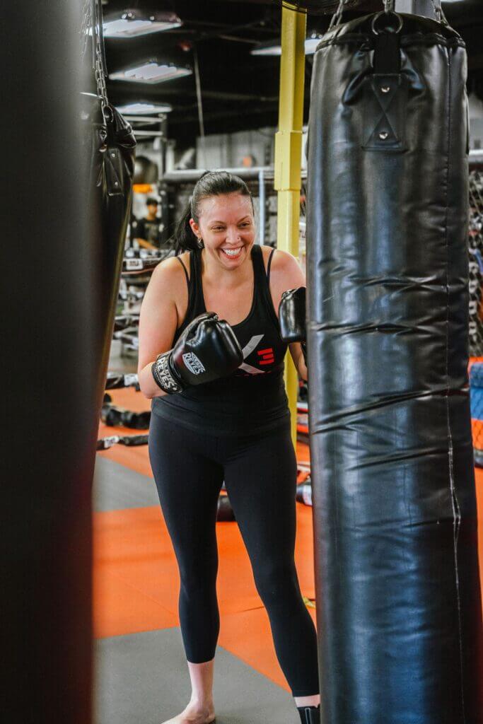 a picture of a smiling person during a women's kickboxing class.