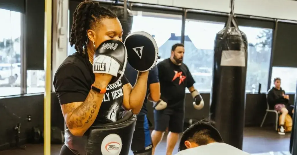 Boxing personal trainer holding mitts while coaching a student in a gym