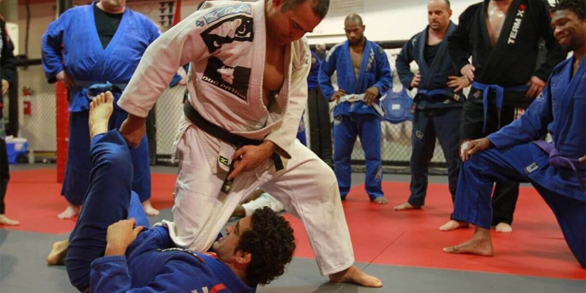 Instructor demonstrating a grappling move in a BJJ class.